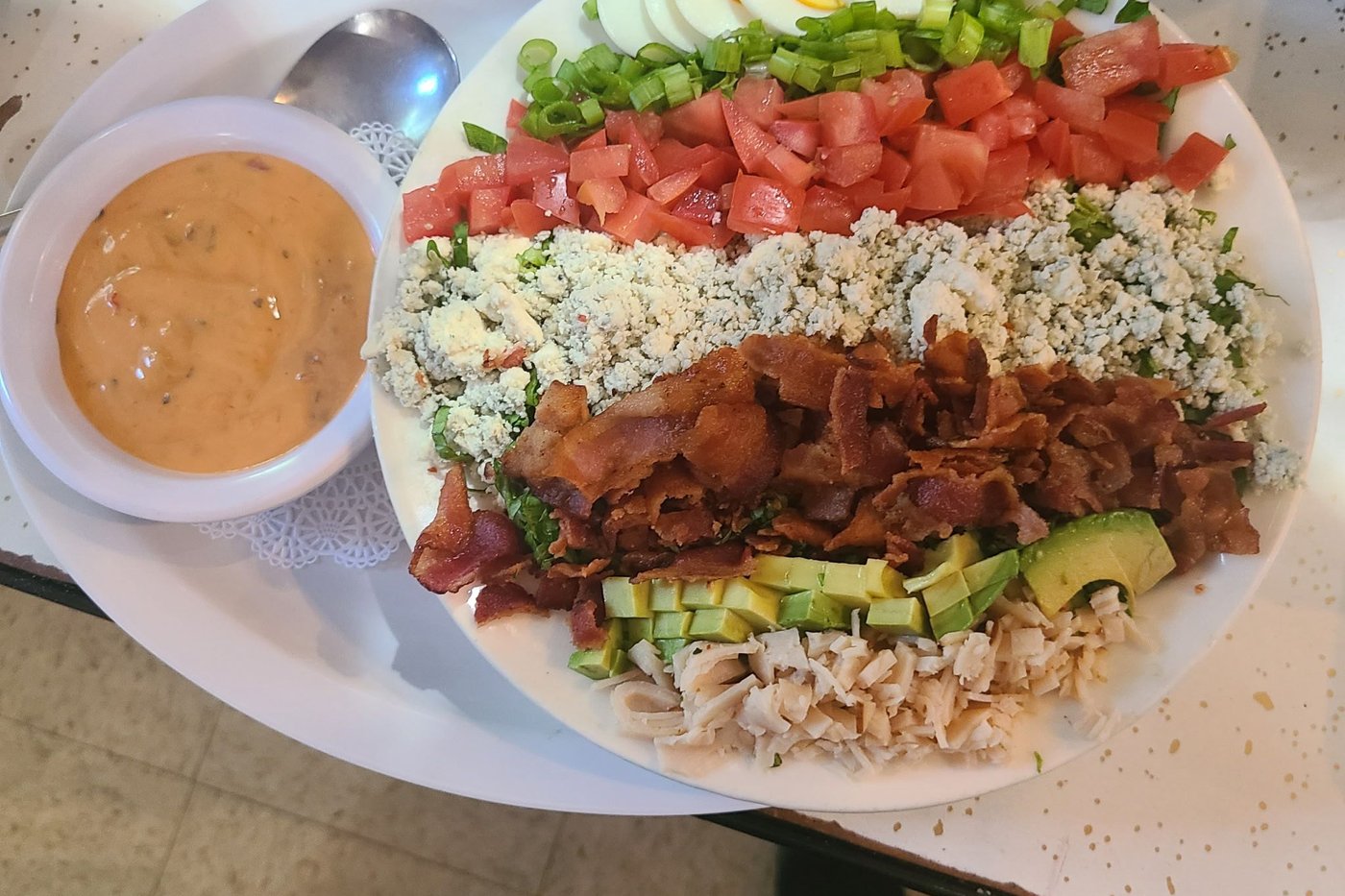 A Cobb salad rowed with egg, bacon, tomato, blue cheese and avocado