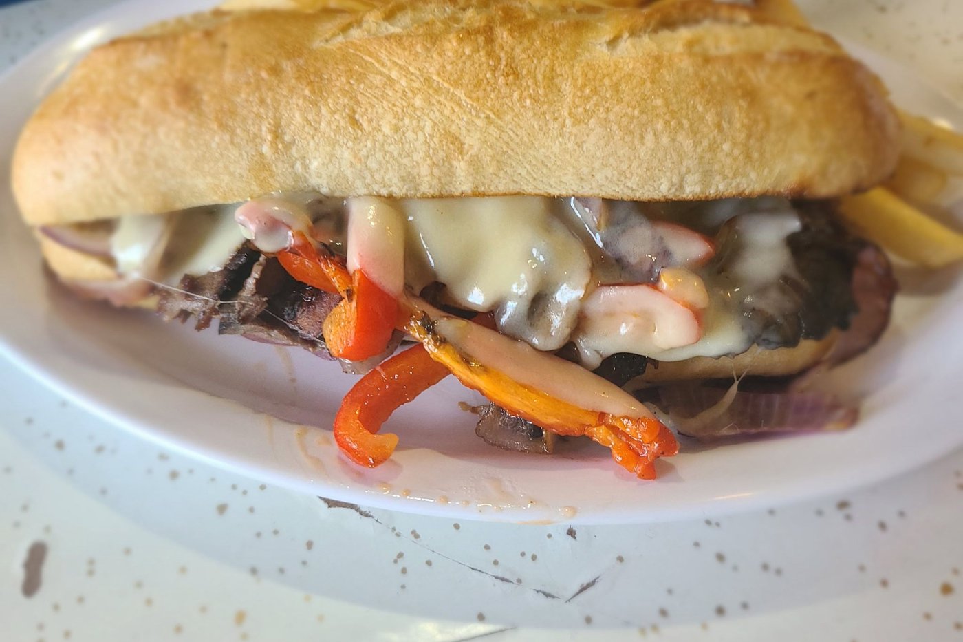 The Philly cheesesteak — griddled steak, peppers and melted cheese on a roll, with fries