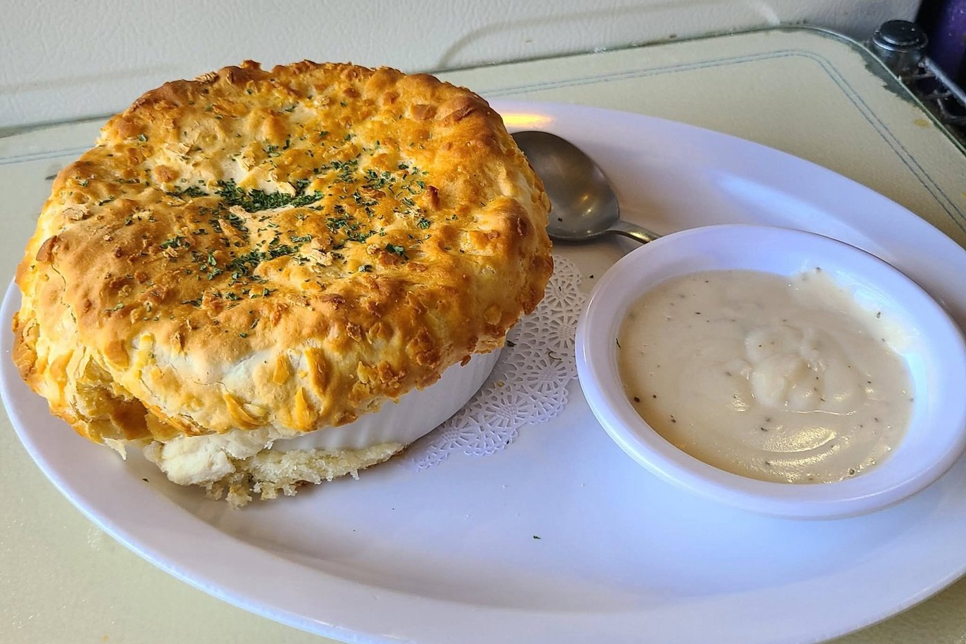 The breakfast pot pie — a golden biscuit crown over a ramekin, with a side of country gravy
