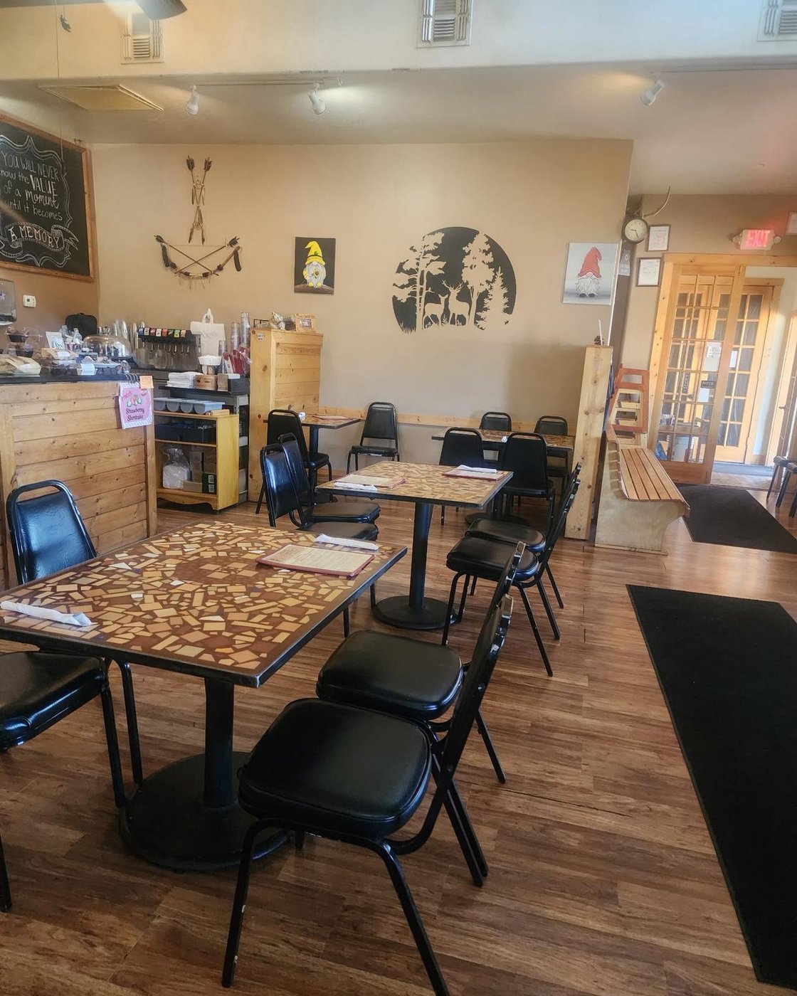 Inside Three Bear's Cafe — mosaic tables set with menus, the deer mural on the wall